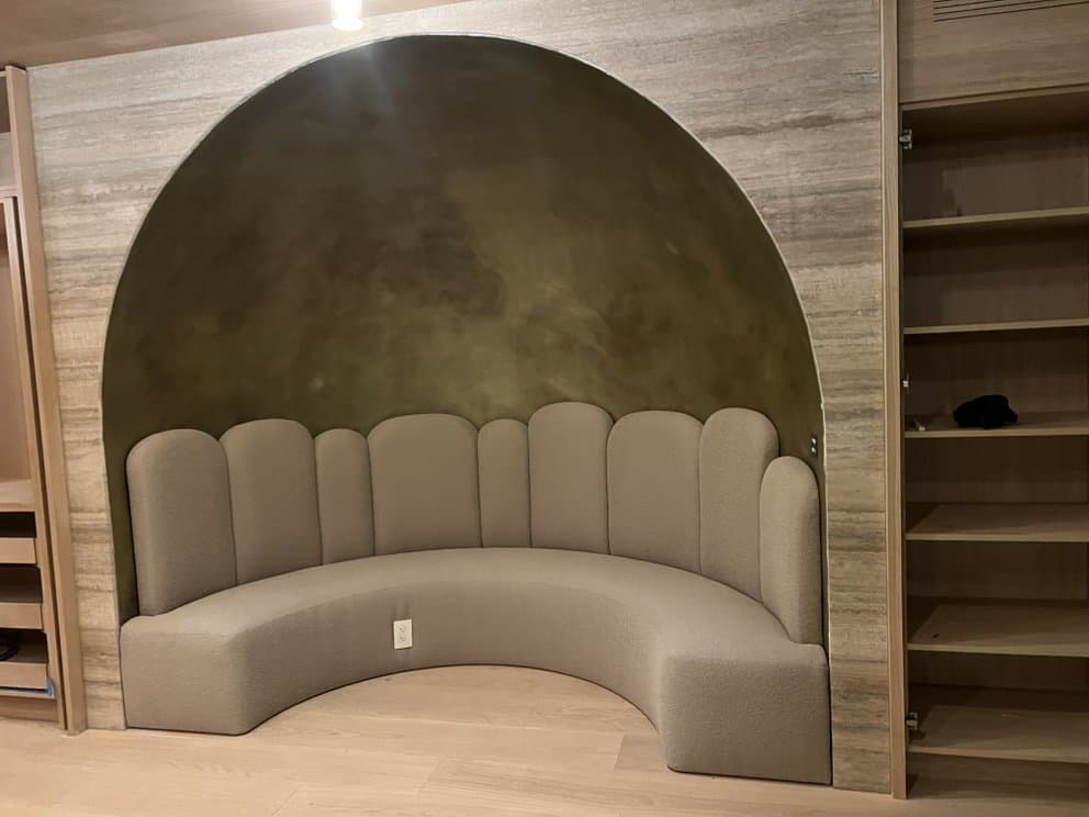 Curved bouclé banquette with scalloped back built into an arched alcove