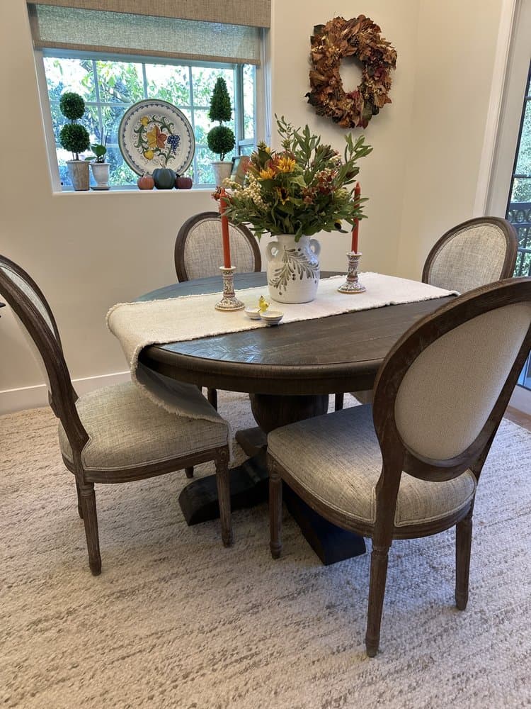 Oval-back dining chairs reupholstered in textured linen around a round table