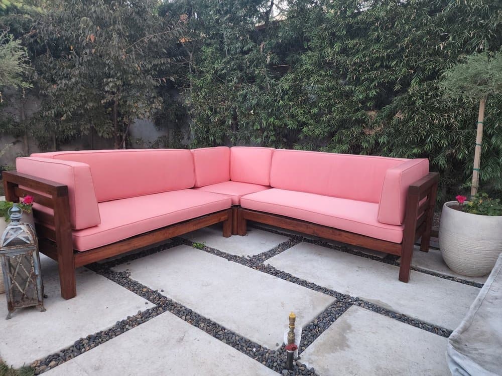 Wood outdoor sectional with new coral cushions on a garden patio